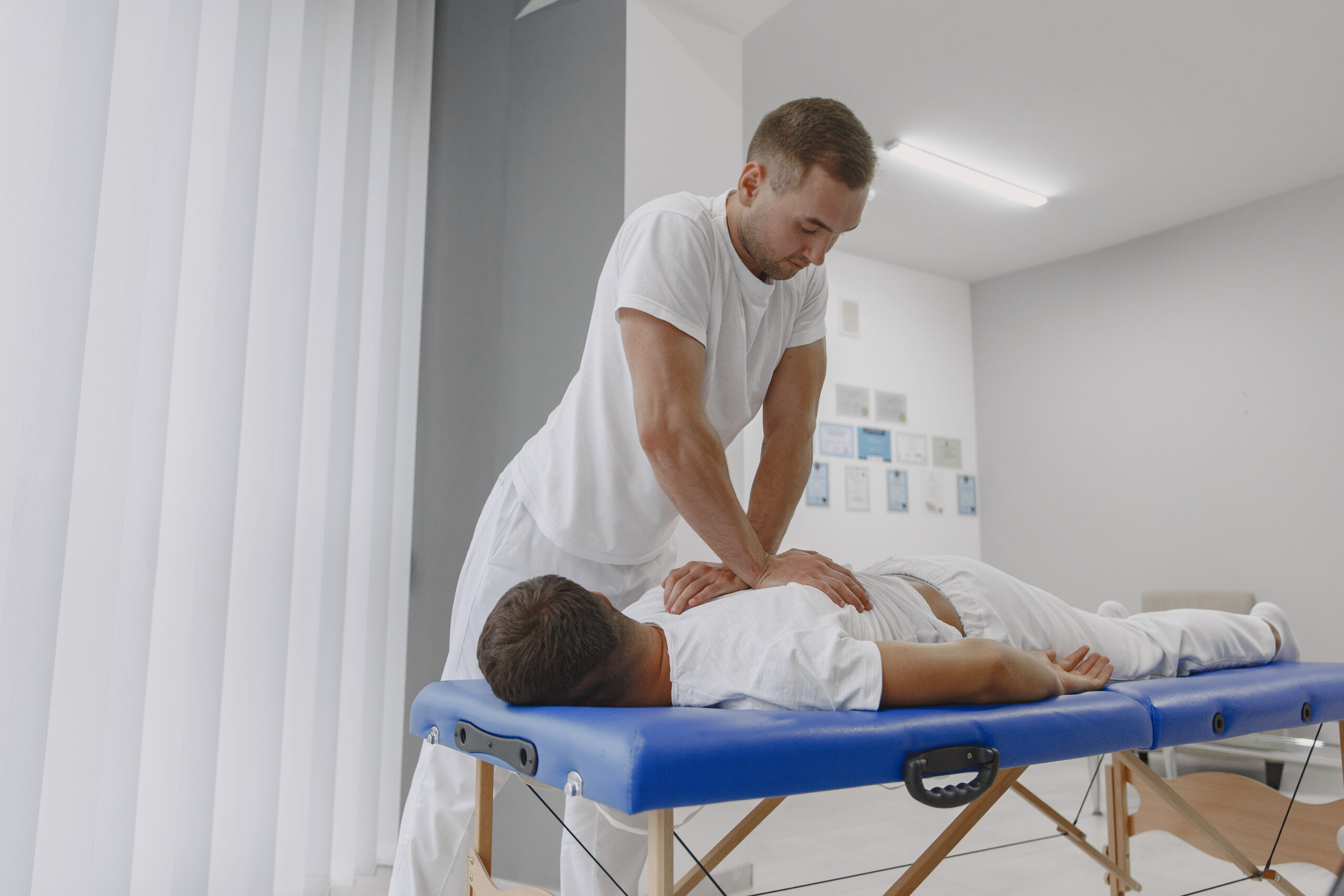Male physiotherapist massaging man's back Private Pilates Lessons in NYC